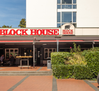Außenansicht des BLOCK HOUSE Frankfurt Westend mit Terrasse, Eingang zum Steakhouse und Gästen im Außenbereich