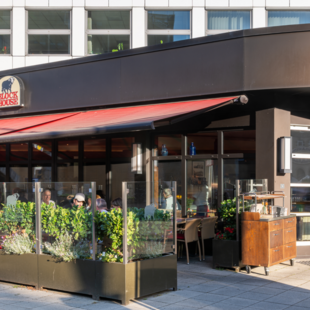 Außenansicht des BLOCK HOUSE Hannover am Thielenplatz mit Terrasse und Gästen im Außenbereich.