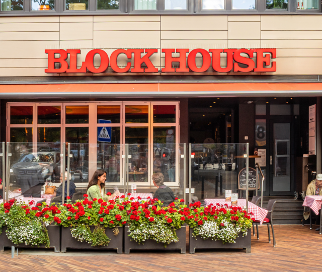 Außenansicht des BLOCK HOUSE Steakhouse in Hamburg Harburg mit Terrasse und Gästen im Außenbereich