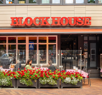 Außenansicht des BLOCK HOUSE Steakhouse in Hamburg Harburg mit Terrasse und Gästen im Außenbereich