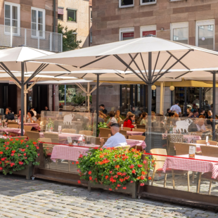 Speisende Gäste auf der sonnengeschützten Terrasse des BLOCK HOUSE Restaurants in Nürnberg