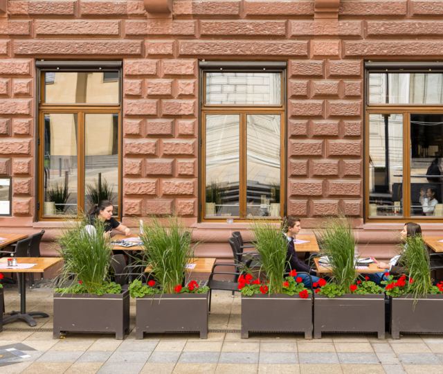 Außenansicht des BLOCK HOUSE Frankfurt am Börsenplatz mit Terrasse, begrüntem Außenbereich und Gästen vor dem Restaurant.