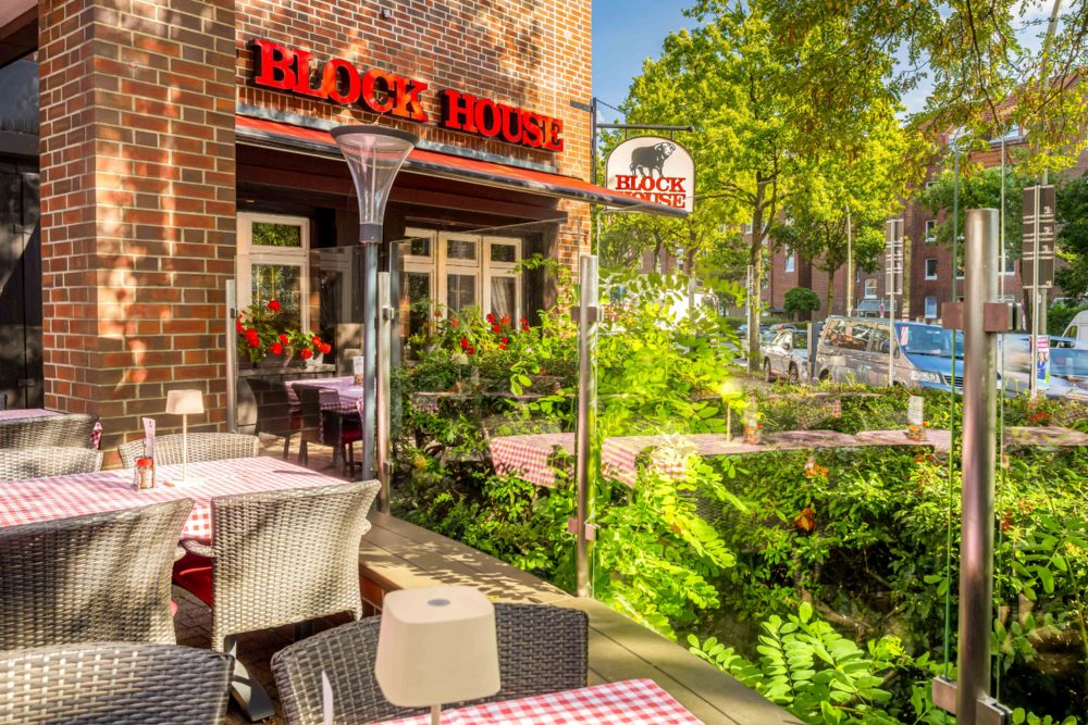 Terrasse vor dem BLOCK HOUSE Hamburg Eidelstedt mit Tischen und rot-weiß karierten Tischdecken vor dem Restaurant
